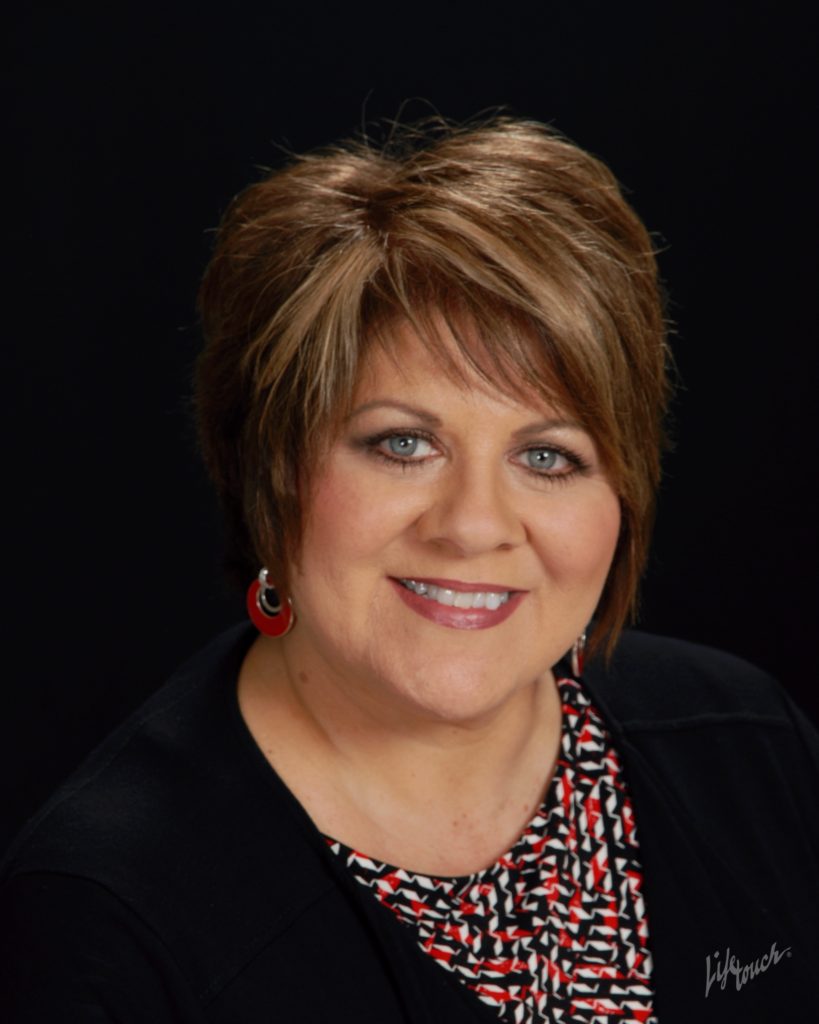 Smiling woman with short brown hairstyle.