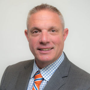 Man in suit with striped tie smiling.