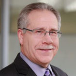 Man with glasses and mustache, wearing suit.
