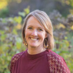 Smiling woman outdoors in a garden setting.