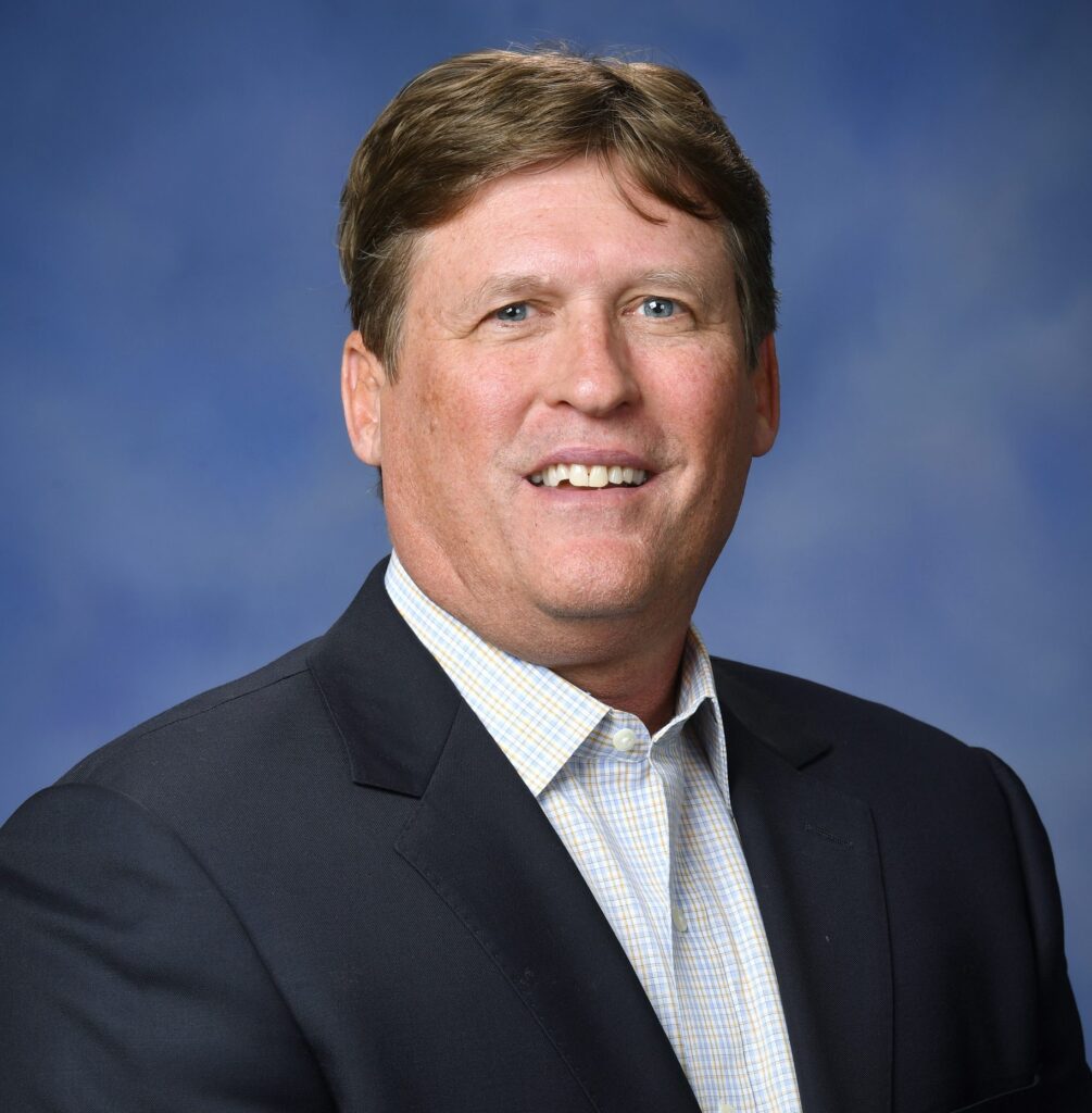 Smiling man in suit with blue background.