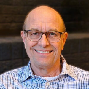 Man wearing glasses and checkered shirt smiling.