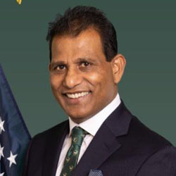 Man in suit smiling beside flag