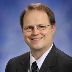 Smiling man in a suit and glasses.