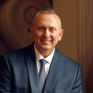 Man in blue suit smiling warmly.