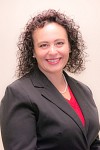 Smiling person in a suit with curly hair.
