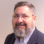 Smiling man with a beard and glasses.